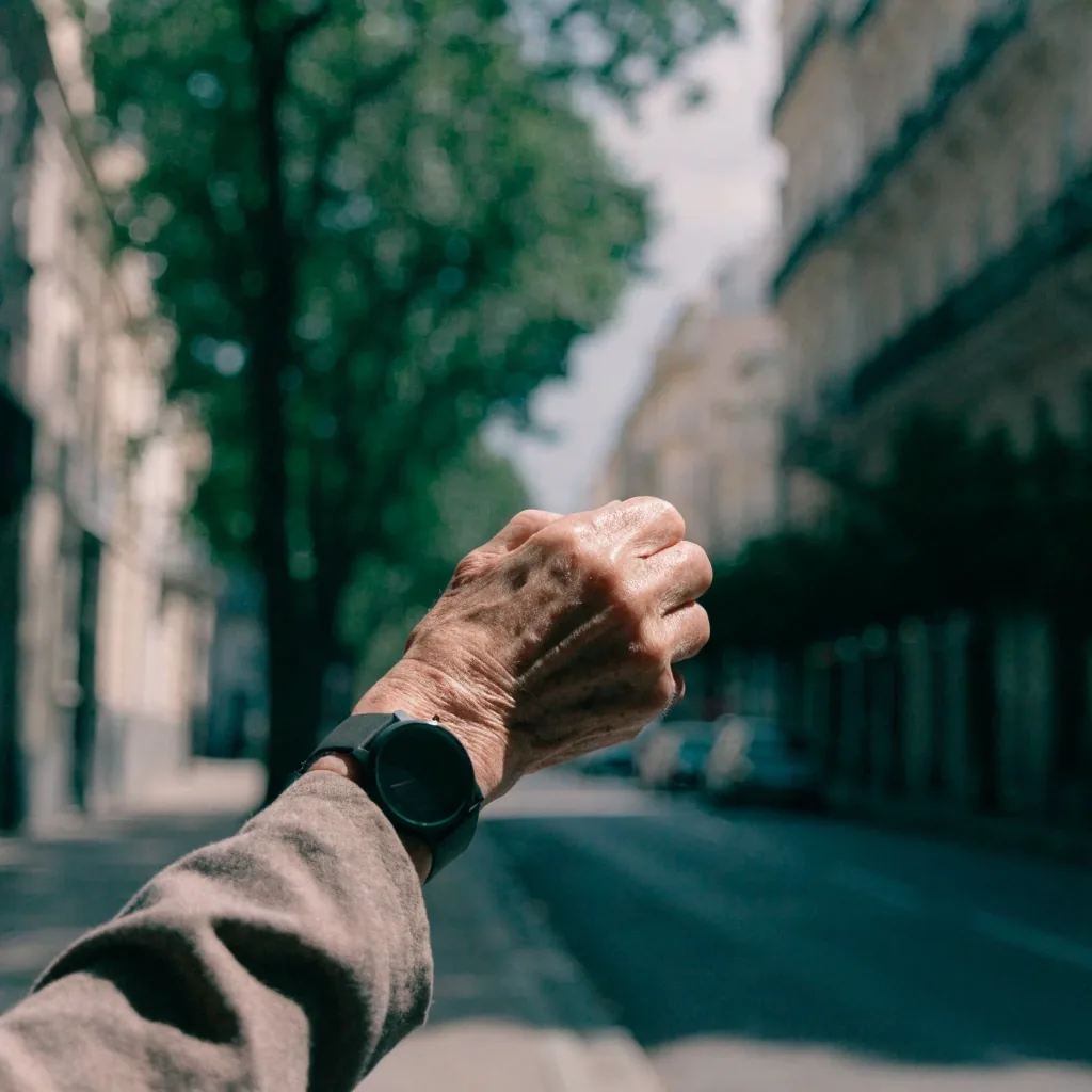 Persona mayor caminando por una vereda porteña en la mañana con un reloj en la muñeca